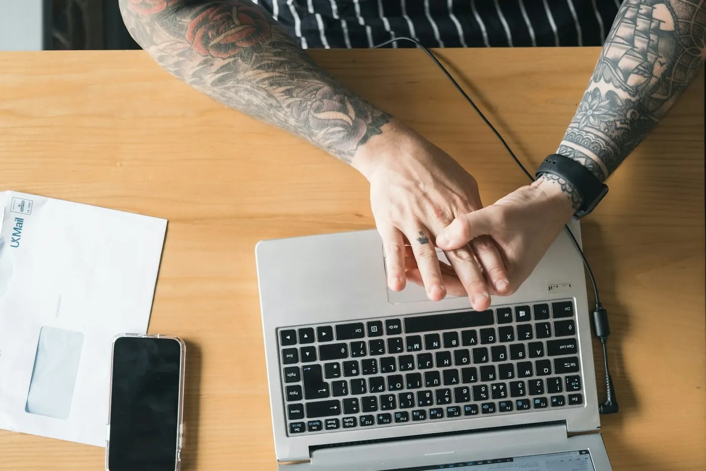 Hands on a laptop at a wooden desk