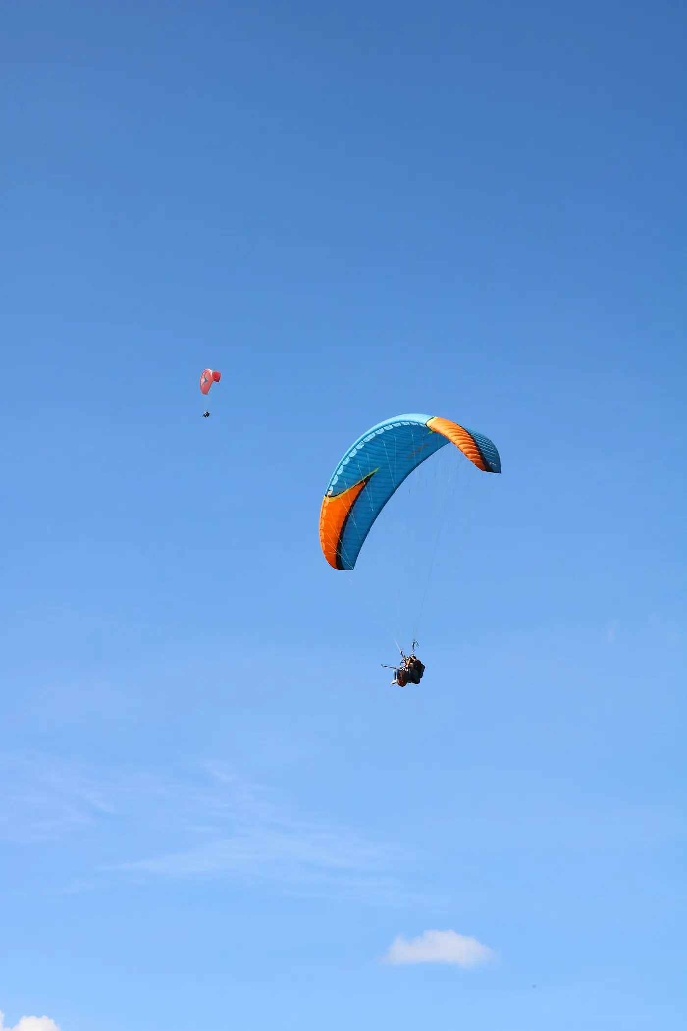A paraglider against a deep blue sky