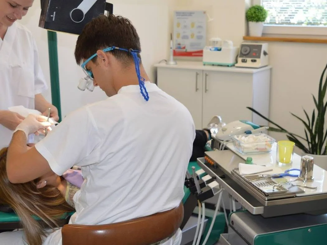 Dr. Sremčević at work in his practice, with his assistant beside him