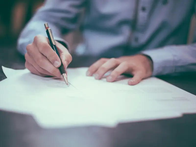 A hand signing a written document