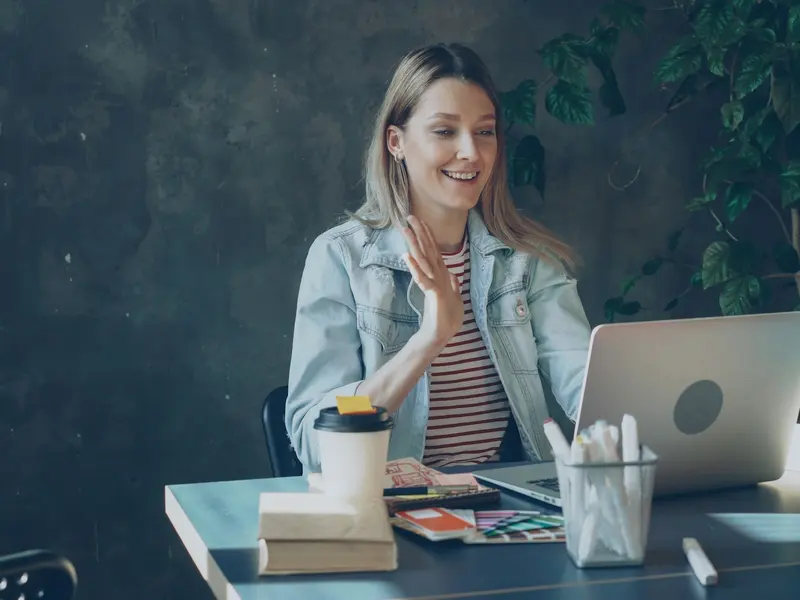 A woman waving on a video call